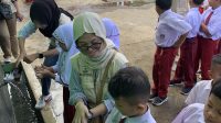 Mahasiswa KKN UNAND saat memandu siswa SD cara mencuci tangan dengan benar. (doc. KKN UNAND)