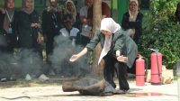 acara Salah satu mahasiswa KKN 20 UINSA saat mendemonstrasikan cara memadamkan api. (doc. KKN 20 UINSA)