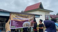 Pemasangan spanduk di warung milik bu ati. (doc. Kukerta MBKM UNRI 2024 Desa Rambah Tengah Hulu)