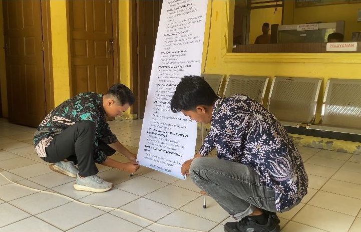 Mahasiswa KKN MBKM UNRI saat melakukan pemasangan stand banner. (doc. Tim KKN MBKM FISIP UNRI Kampung Tanjung Kuras)