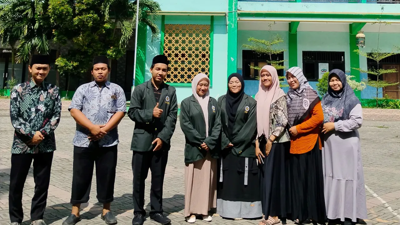 Para mahasiswa UINSA berfoto dengan para guru MA UNGGULAN BUSTANUL HIKMAH di depan gedung sekolah sebagai simbol kerja sama dan kolaborasi pendidikan. (doc. Shofi Amirah Masrufah dan Refa Jihan/UINSA)