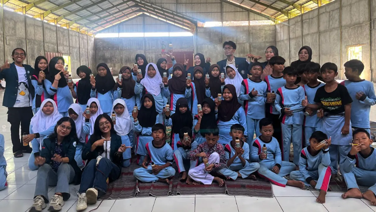 Mahasiswa kelompok 1 KKN-T 35 UNDIP berfoto bersama anak-anak SDN 02 Tambakbulusan dengan sabun ecoenzym yang telah dibuat bersama (21/5/2025). (doc. Kelompok 1 KKN-T 35 UNDIP)