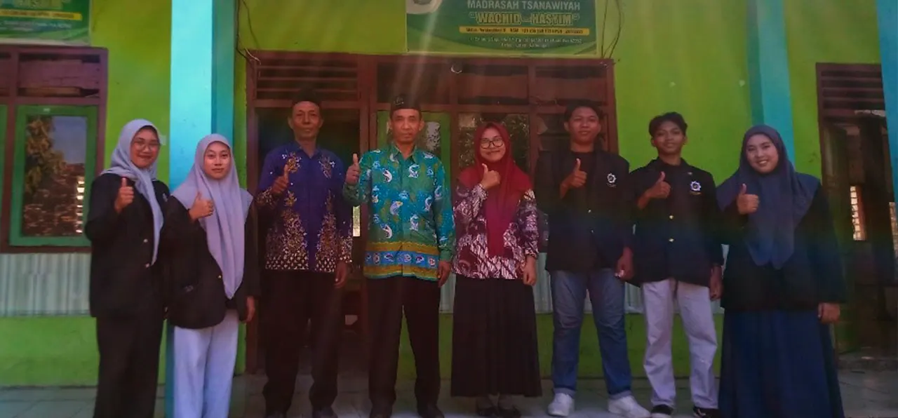 Para mahasiswa UINSA foto bersama dengan para guru MTs Wachid Hasyim  di depan Gedung sekolah sebagai bentuk bukti terjalin kerja sama demi mewujudkan kegiatan sosialisasi moderasi beragama. (doc. Dewi/ salah sati siswa MTs Wachid Hasyim)