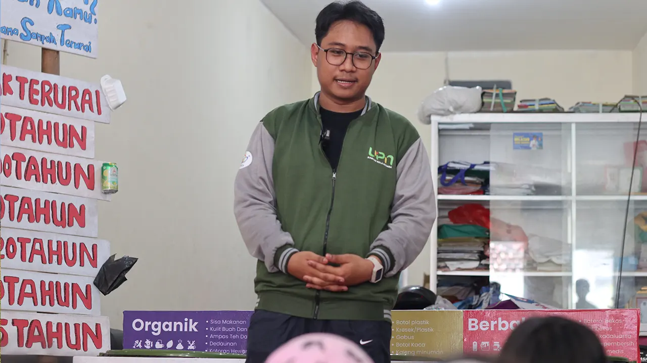 Foto Ahmad Baihaqi Yudhistira pemateri sosialisasi tentang pengelolaan sampah dan papan informasi waktu dari berbagai macam sampah dapat terurai. (doc. Kel 37 KKN UPNVJT)