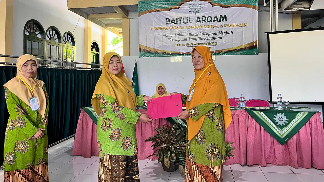 Ketua Pelaksana Baitul Arqam PCA Cikedal, Aam Siti Aminah, S.Pd., secara simbolis menyerahkan dokumen kepada salah satu peserta sebagai bentuk apresiasi dan peneguhan komitmen kaderisasi, di Gedung Majelis Taklim Rhoudatul Jannah. (doc. Lapina Lena)