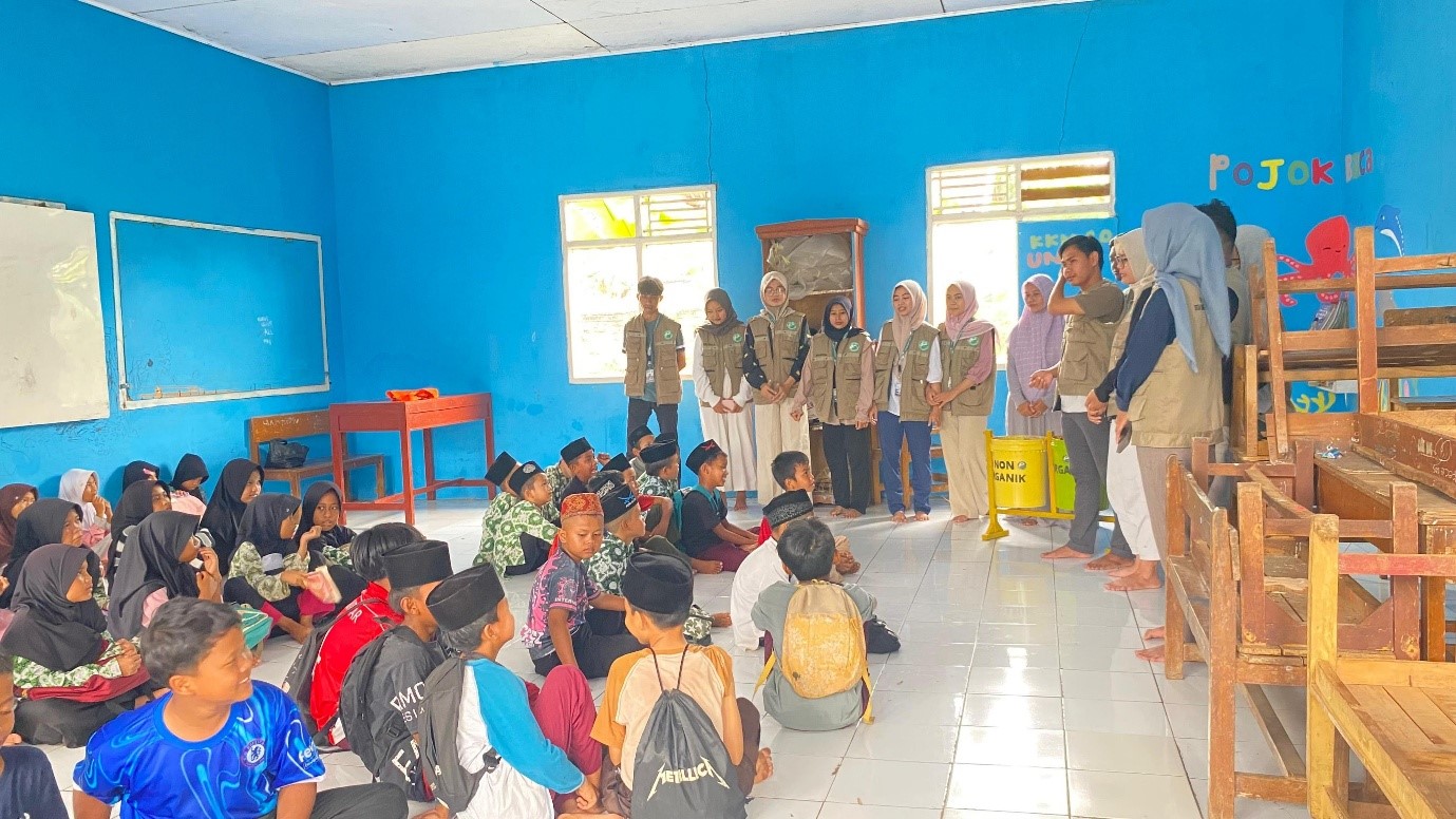Mahasiswa KKM 10 UNIBA saat melakukan kegiatan edukatif Pojok Baca serta menyerahkan bantuan tempat sampah di Madrasah Diniyah Takmiliyah Awaliyah (MD-TA) Nurul Islam. (doc. KKM 10 UNIBA)