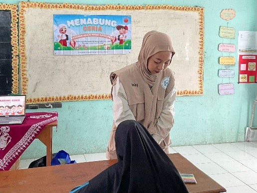 Bening Ajeng Arum Kusuma saat mendampingi siswa mewarnai celengan. (doc. pribadi)