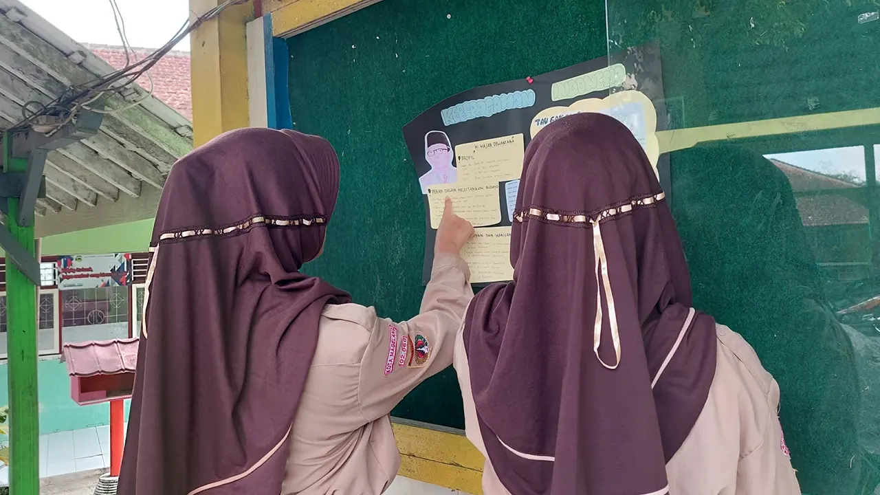 Dua siswi melihat dan membaca mading. (doc. pribadi)