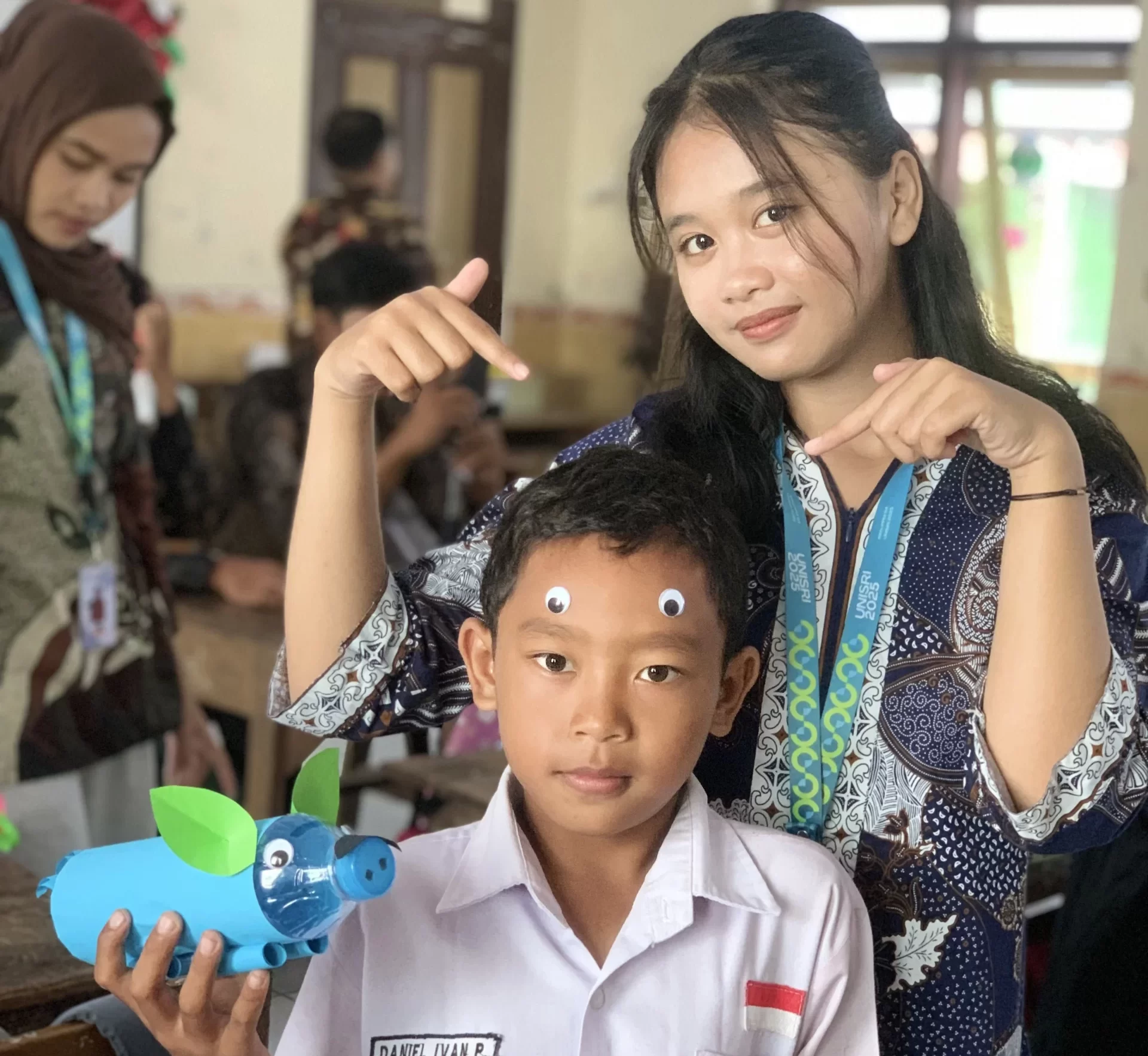 Mahasiswa KKN UNISRI mendampingi siswa SD N 1 Duwet saat praktik membuat celengan dari botol bekas dalam sosialisasi hidup hemat sejak dini di Kecamatan Ngawen, Klaten, Selasa (29/7/2025). (doc. pribadi)