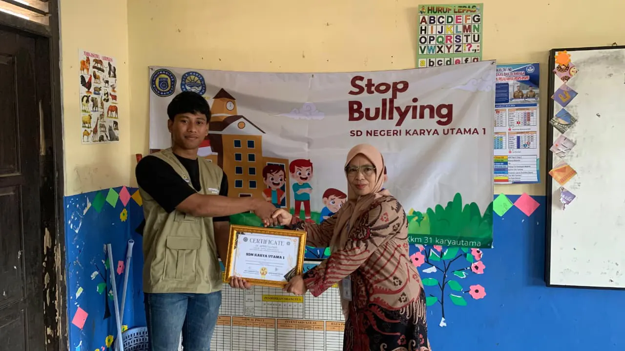 Koordinator KKM Kelompok 31 bidang hukum, menyerahkan sertifikat apresiasi kepada Kepala SDN Karya Utama 1, sebagai bentuk penghargaan atas dukungan selama pelaksanaan program kerja. (doc. KKM 31 UNIBA)