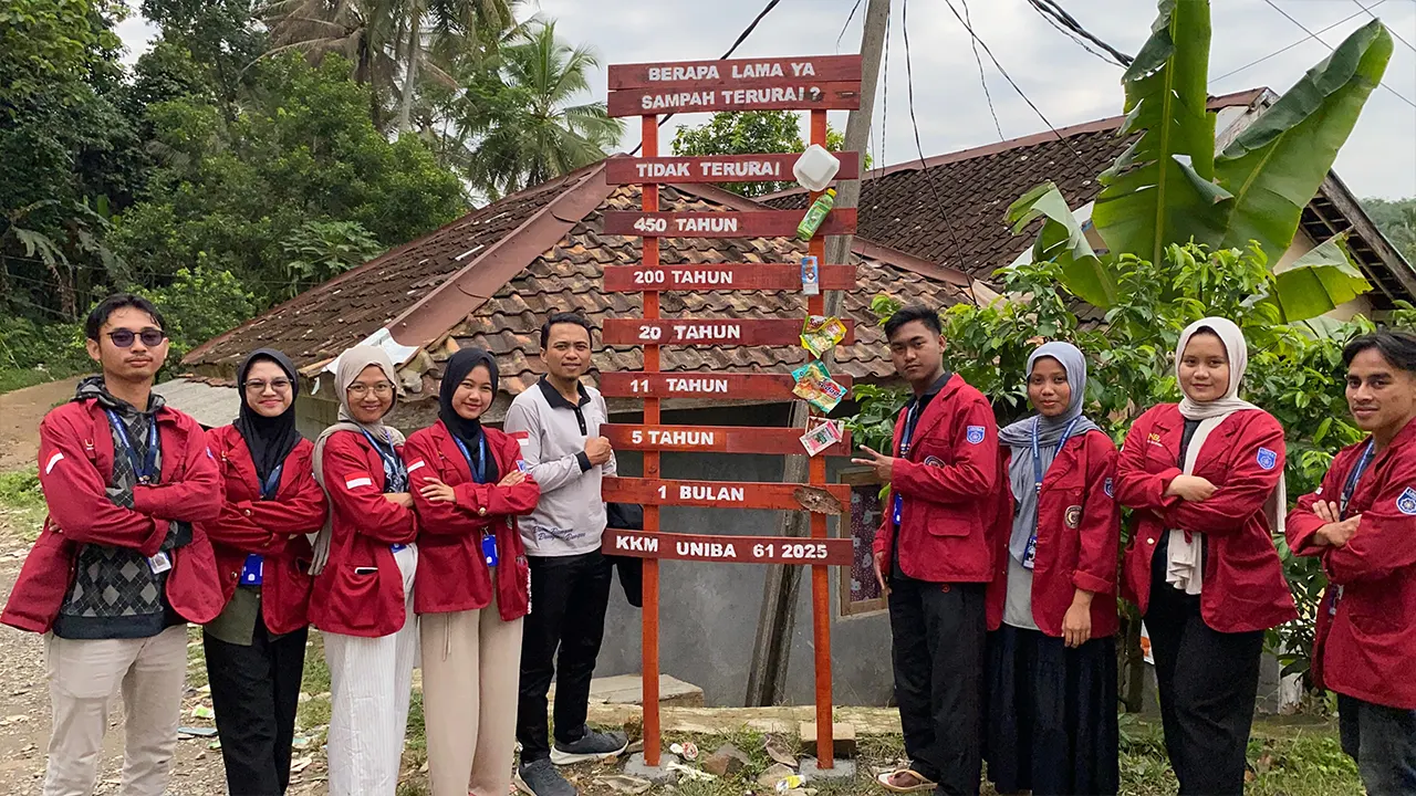 Mahasiswa KKM 61 UNIBA berpose di depan papan informasi edukasi waktu terurai sampah yang mereka pasang di Desa Margaluyu, sebagai upaya meningkatkan kesadaran masyarakat terhadap pentingnya pengelolaan sampah ramah lingkungan. (doc. KKM 61 UNIBA)