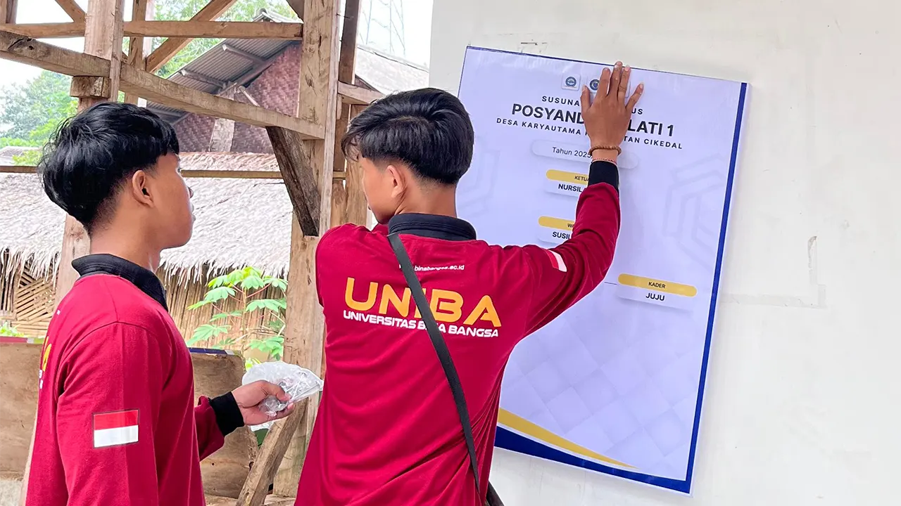 Mahasiswa KKM UNIBA Kelompok 31 memasang banner struktur kepengurusan Posyandu di Kampung Cilanggawe, sebagai bentuk dukungan terhadap transparansi dan akses informasi layanan kesehatan masyarakat. (doc. KKM Kelompok 31 UNIBA)