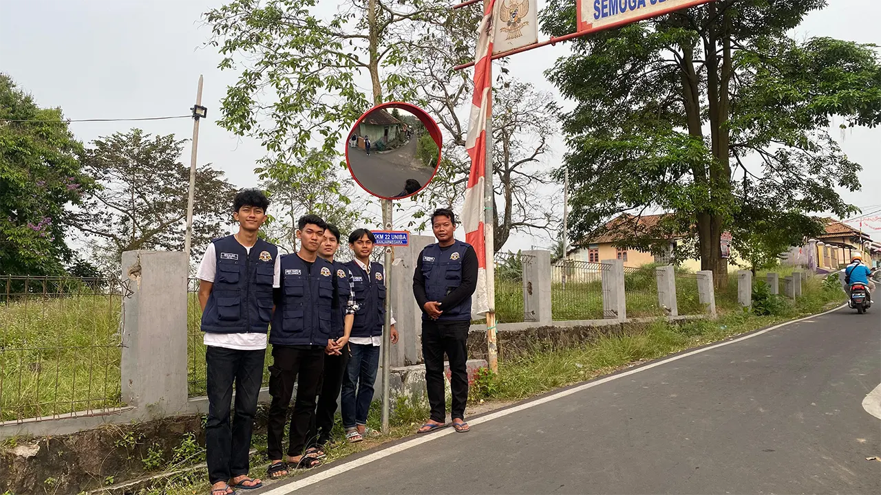 Mahasiswa KKM22 UNIBA berfoto di lokasi pemasangan cermin cembung di pertigaan Kampung Temugiring Tengah, Desa Banjarnegara, Kecamatan Ciwandan, Jumat (8/8/2025). (doc. KKM 22 UNIBA)