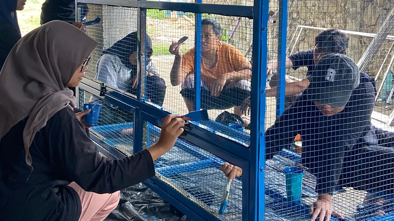 Mahasiswa KKN 212 UNS saat melakukan pengecatan bak sampah. (doc. KKN 212 UNS)