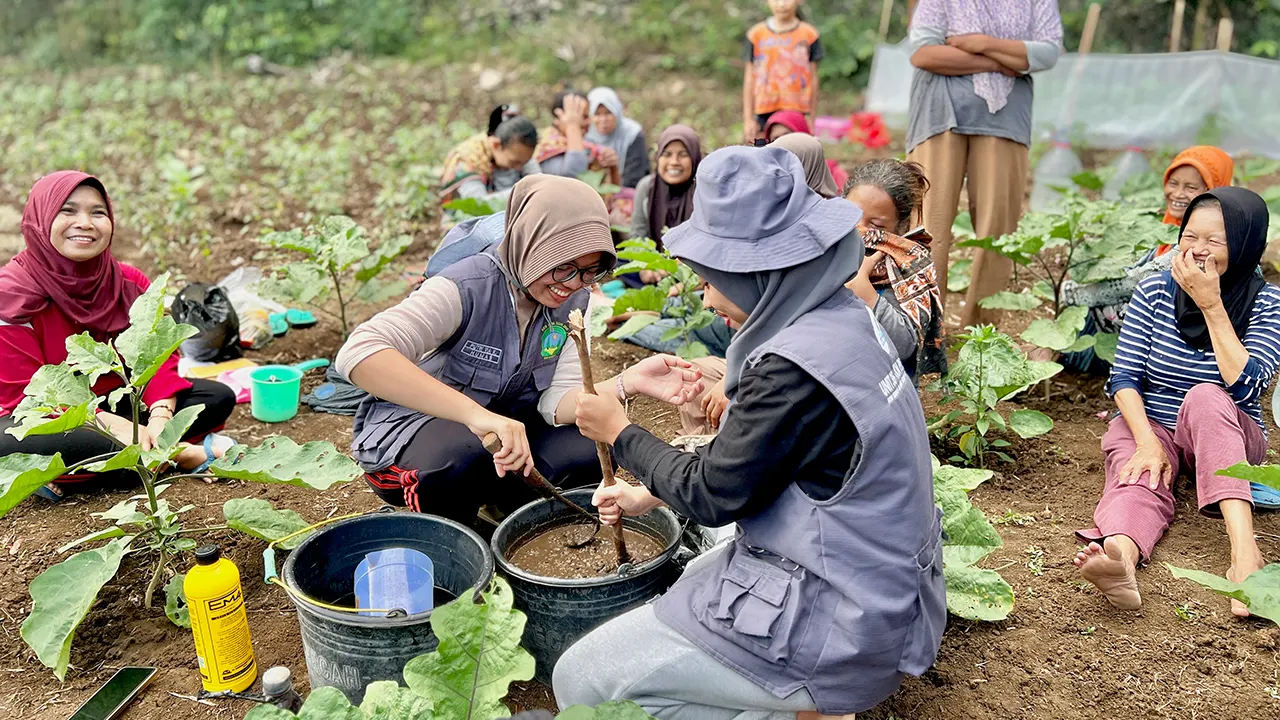 Mahasiswa KKN-PPM 35 UMBY bersama anggota KWT Seropan III mempraktikkan pembuatan POC di kebun sayur warga, disambut antusias dan penuh canda tawa. (Doc. KKN-PPM 35 UMBY 2025)