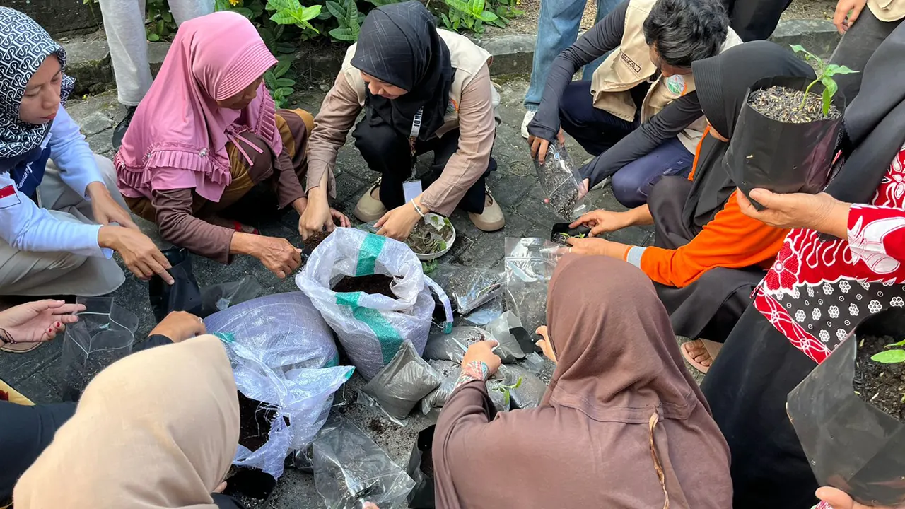 Mahasiswa KKN UNS saat mendampingi peserta saat mengaplikasikan sekam bakar untak tanaman dalam polibag. (doc. KKN UNS Desa Legundi)