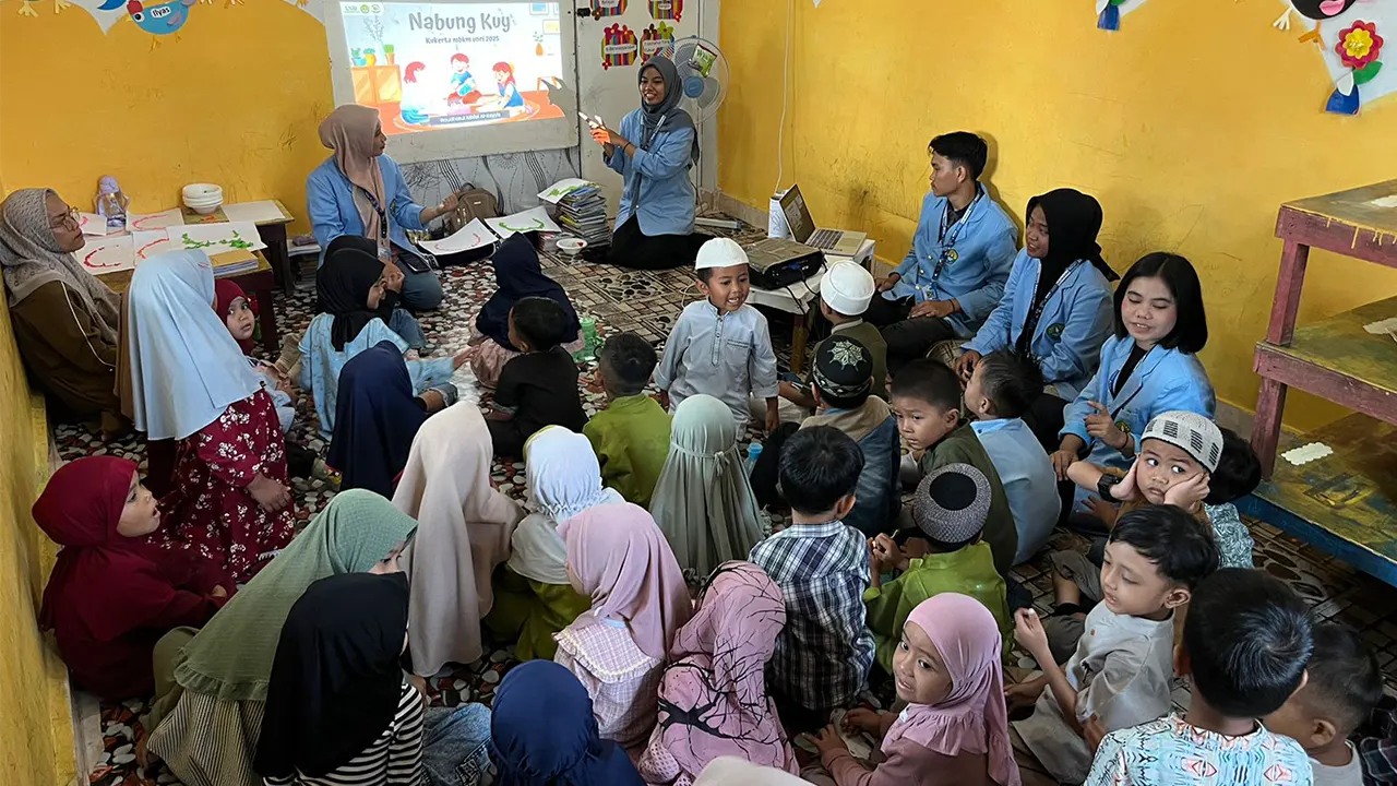 Mahasiswa Kukerta MBKM UNRI saat memberikan edukasi interaktif “Nabung Kuy & Pilah Yuk” kepada siswa RA Al-Kayyis, Kelurahan Bencah Lesung, dengan metode dongeng dan permainan yang mengajarkan pentingnya menabung serta memilah sampah sejak usia dini. (doc. Kukerta MBKM UNRI)