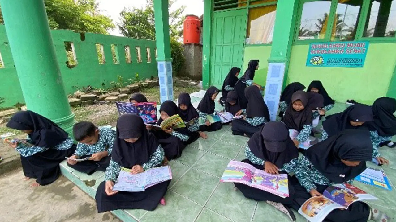 Para siswi Madrasah Ibtidaiyah Desa Bojot asyik membaca buku cerita yang dibawa Mobil Pintar dalam program literasi yang digagas KKM 85 UNIBA bersama Perpustakaan Provinsi Banten, Kamis (7/8/2025). (doc. KKN 85 UNIBA)