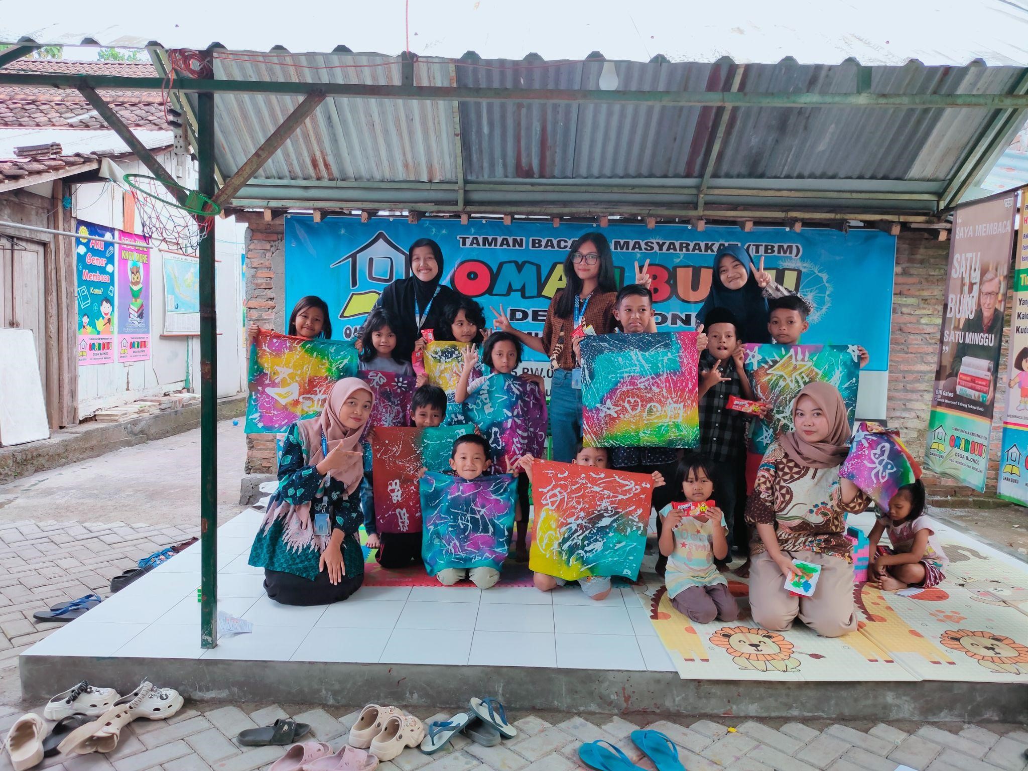Mahasiswa UNS bersama anak-anak Desa Blondo menunjukkan hasil karya batik ciprat usai kegiatan literasi kreatif di TBM Omah Buku Blondo, Kecamatan Mungkid, Kabupaten Magelang. (doc. KKN 162 UNS)