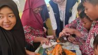 Siswa SDN 2 Tambakan antusias menyaksikan ledakan miniatur gunung berapi dan berdiskusi dengan mahasiswa KKN, tampak fokus dan seru mengikuti eksperimen. (dok. KKN 107 UNS)