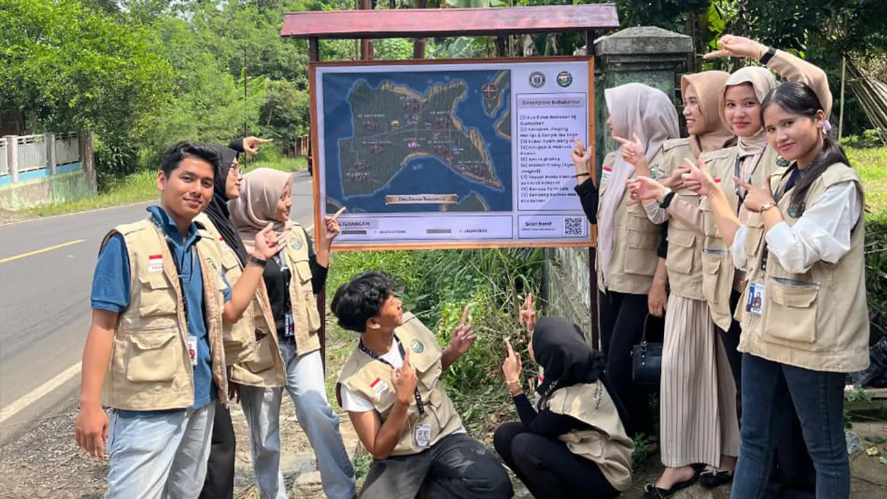 Mahasiswa KKM 26 UNIBA Babakanlor berfoto bersama di depan papan DesaXplore, denah inovatif yang mereka buat untuk memperkenalkan potensi UMKM dan lokasi penting desa kepada masyarakat dan pengunjung. (doc. KKM 26 UNIBA)