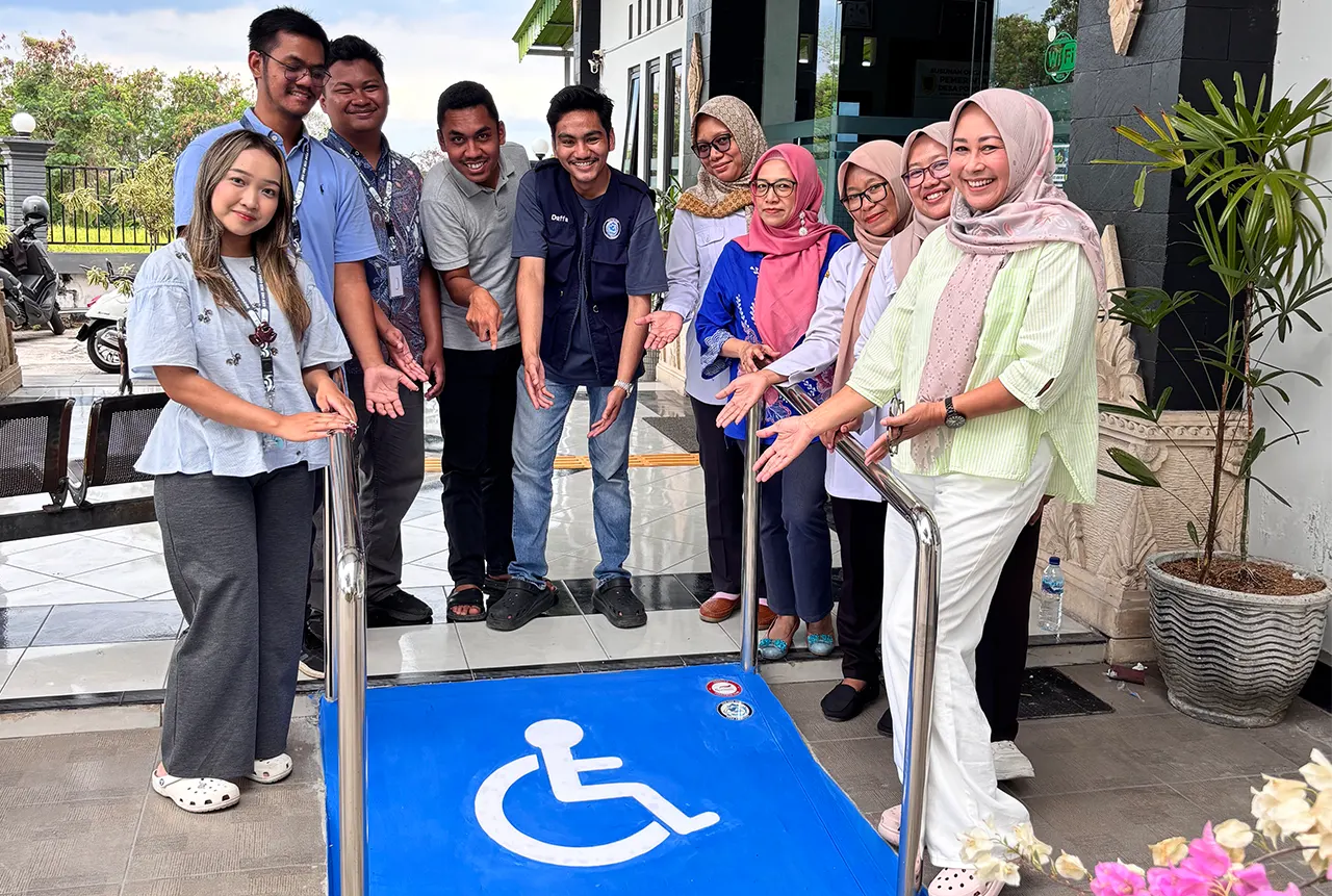 Mahasiswa KKN UNS bersama perangkat desa dan perwakilan NPC Indonesia berfoto di depan jalur landai ramah disabilitas yang baru dibangun di Kantor Desa Ponggok, Klaten. (doc. KKN 103 UNS)