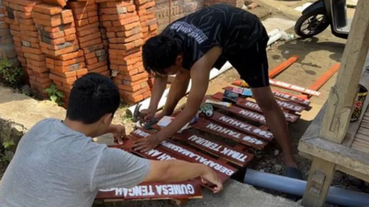 Mahasiswa KKN UNS saat membuat plang edukasi berisi informasi lama waktu penguraian sampah untuk meningkatkan kesadaran warga Giri Tembesi. (doc. KKN 136 UNS)