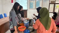 Mahasiswi KKN MAS Kelompok 33 Desa Langsat Permai membimbing warga dalam praktik pembuatan lilin aromaterapi dari minyak jelantah pada workshop di Balai Desa, Senin (1/9/2025). (doc. KKN MAS Kelompok 33)