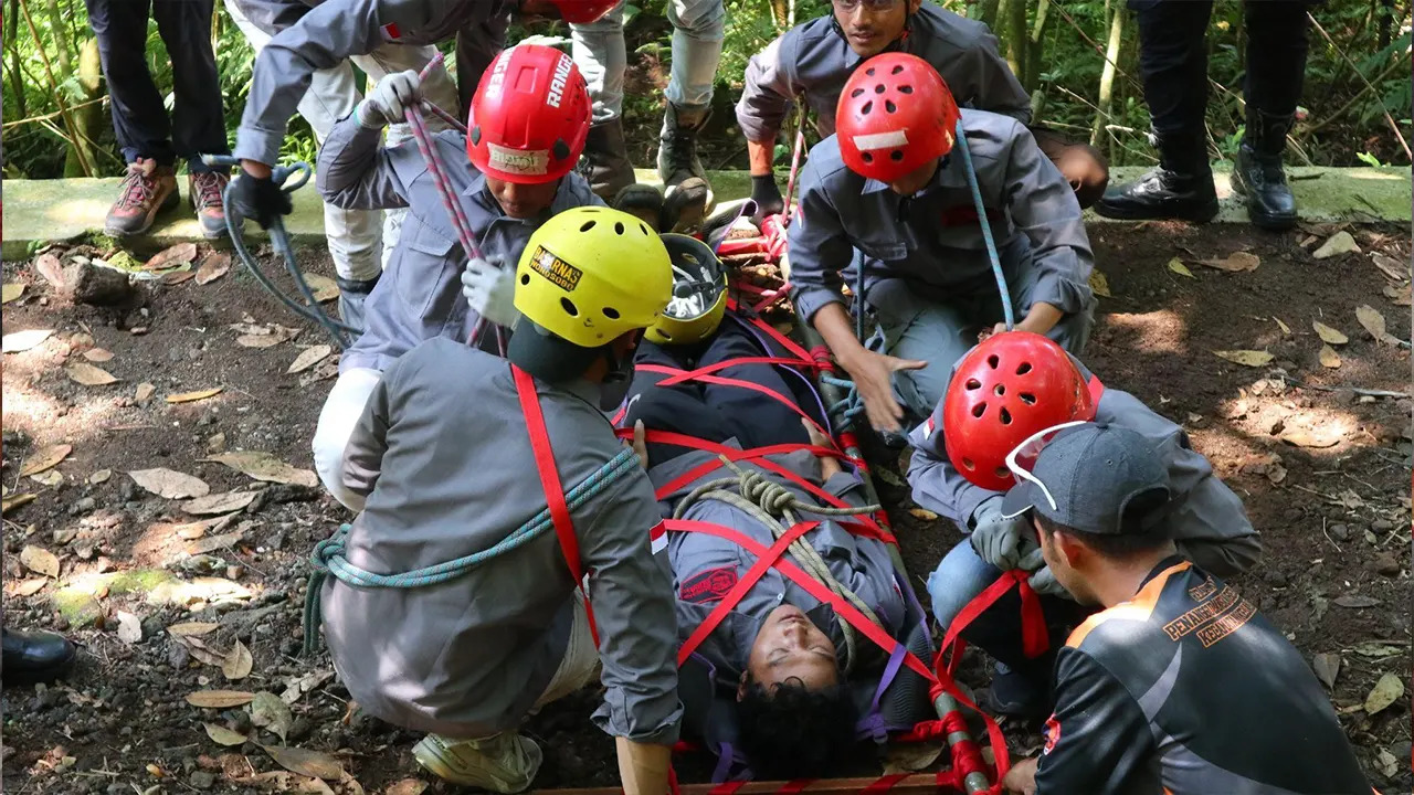 Peserta pelatihan melakukan simulasi evakuasi korban di medan berat dengan menggunakan tandu dan tali pengaman, dibimbing oleh tim BASARNAS Wonosobo dalam kegiatan KKN UNS di Gunung Bismo, Desa Mlandi, Kecamatan Garung. (doc. KKN 363 UNS)