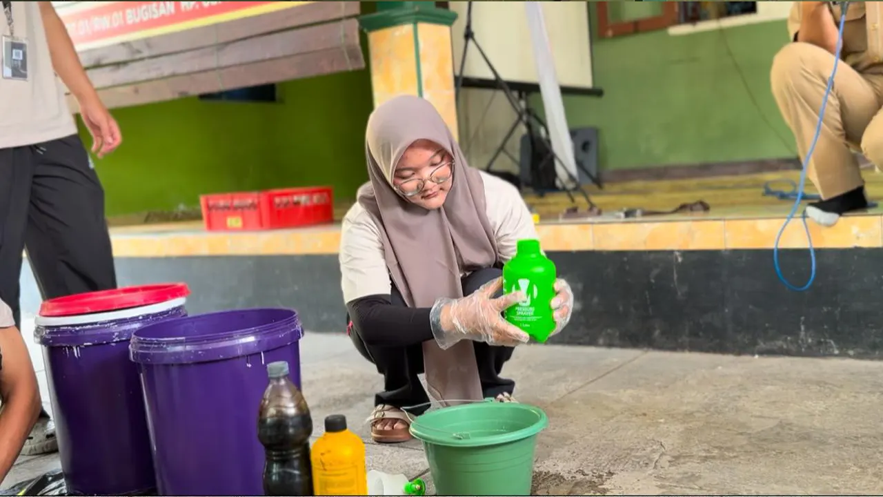 Seorang mahasiswa KKN UNS 2025 Kelompok 120 di Desa Bugisan memperlihatkan hasil olahan limbah organik rumah tangga yang telah difermentasi menjadi pupuk cair. (doc. KKN 120 UNS)