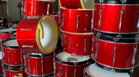 Tumpukan bass drum merah siap dikirim ke berbagai sekolah dan komunitas marching band. Peralatan baru ini jadi penunjang utama performa tim perkusi. (doc. pabrikalatdrumband.com)