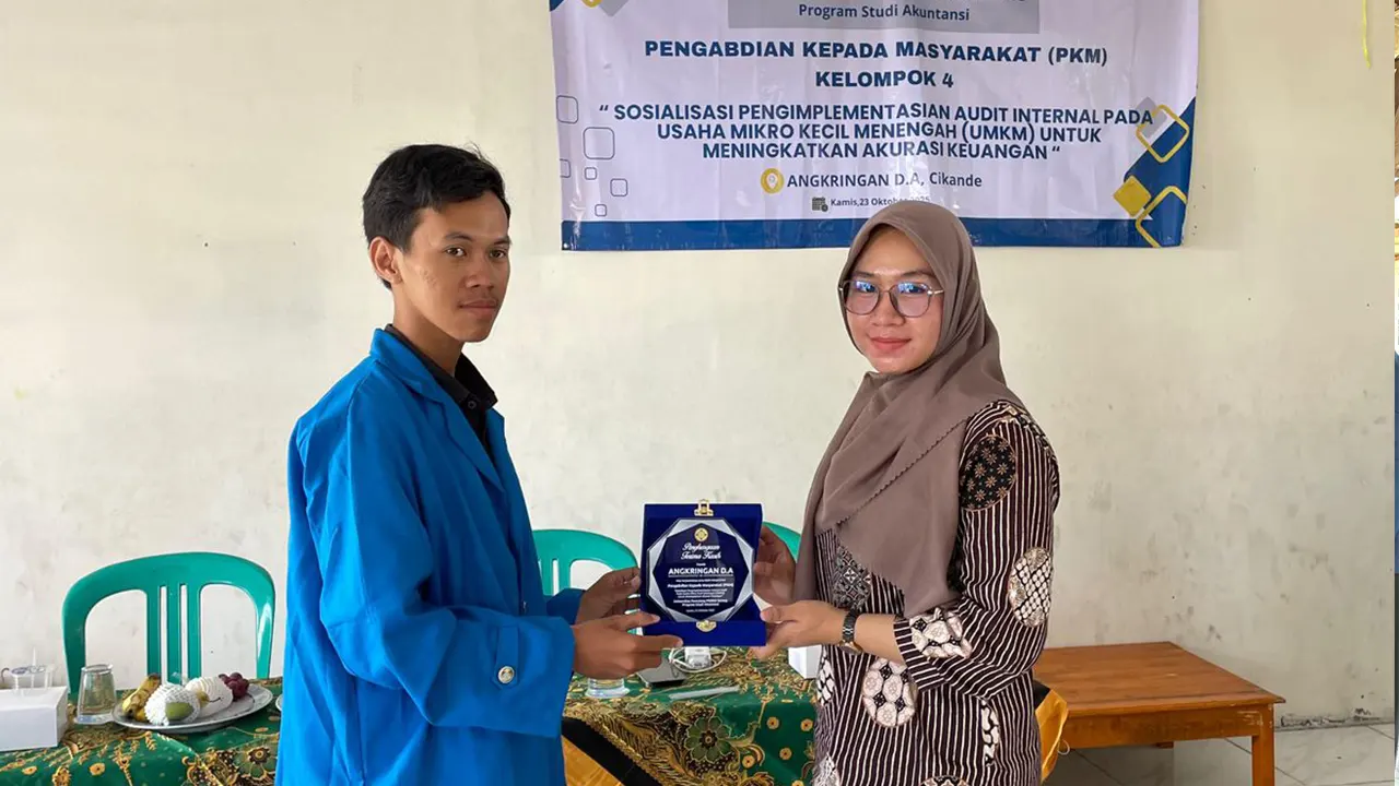 Mahasiswa PKM Universitas Pamulang Kampus Kota Serang, Firman Adriyansyah (kiri), menyerahkan plakat penghargaan kepada perwakilan pelaku UMKM usai kegiatan Sosialisasi Pengimplementasian Audit Internal pada UMKM di Angkringan D.A, Cikande, Kabupaten Serang, Kamis (23/10/2025). (doc. pribadi)