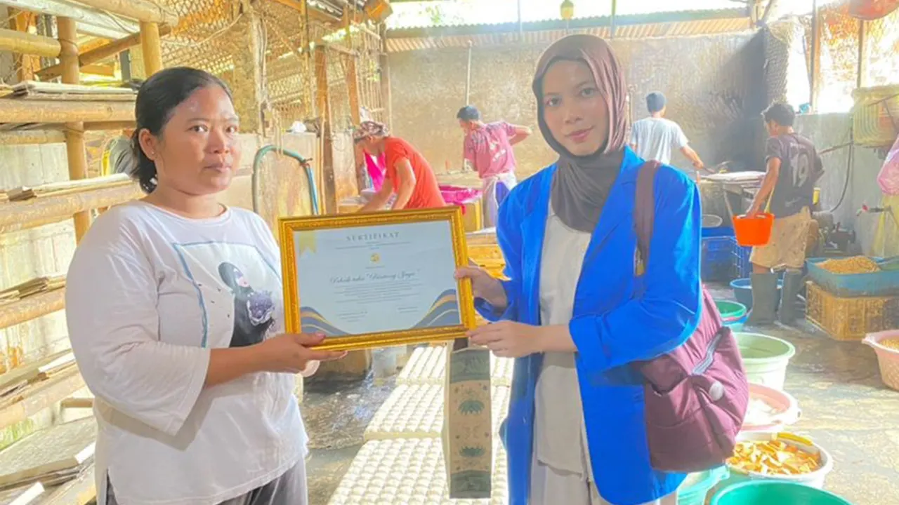 Tim PKM Mahasiswa Universitas Pamulang (Unpam) Kampus Serang, Rohima Maptuha (kanan), menyerahkan sertifikat penghargaan kepada pemilik UMKM Pabrik Tahu Bintang Jaya, Nasri (kiri), usai kegiatan pendampingan penyusunan laporan keuangan sederhana di Kota Serang, Banten, Selasa (14/10/2025). (doc. pribadi)