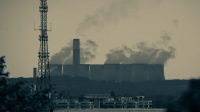 Asap dari cerobong PLTU tampak menggantung di langit kawasan pesisir, menjadi simbol paradoks transisi energi yang masih menyisakan bayang ketidakpastian bagi warga sekitar. Sumber foto: Unsplash