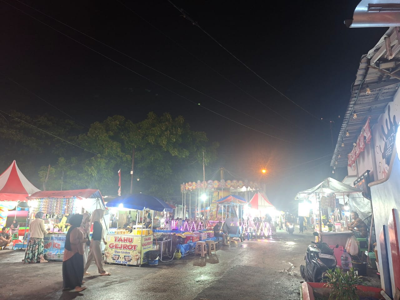 Pengunjung berjalan di area jajanan dan wahana permainan pada pasar malam di Pelabuhan Timur, Kecamatan Kamal, Bangkalan. (doc. pribadi)