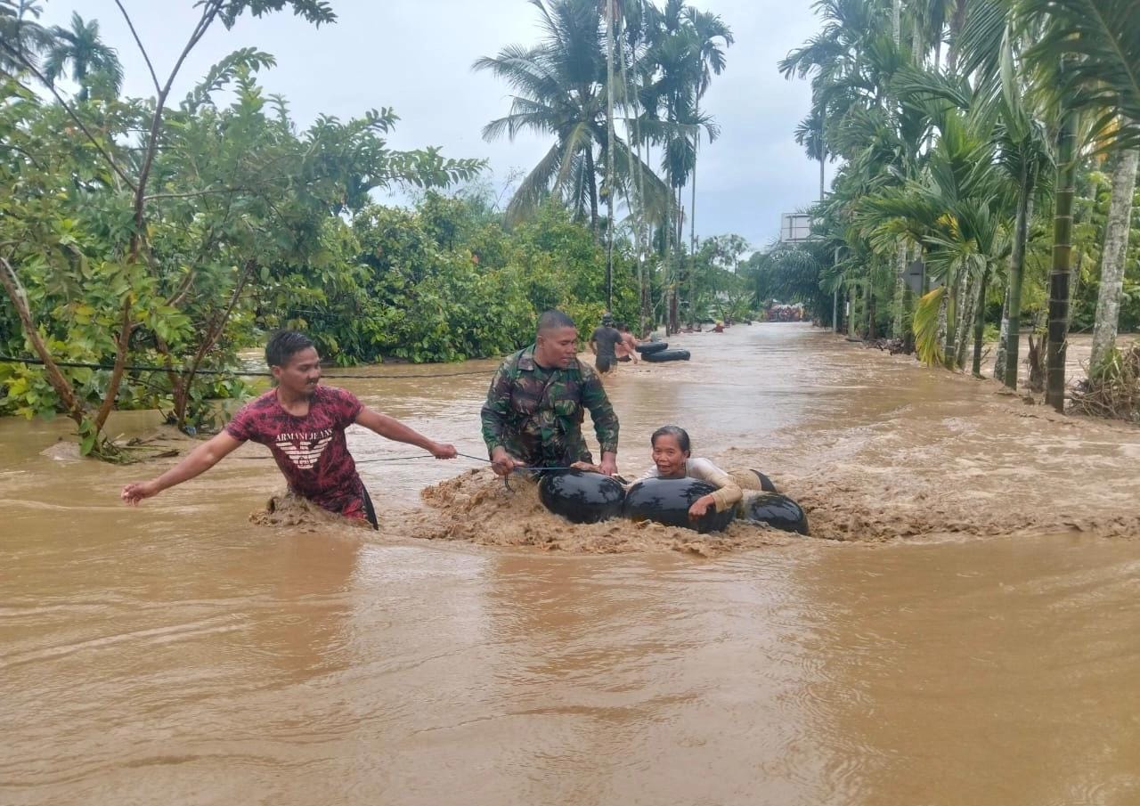 Petugas TNI bersama warga mengevakuasi seorang lansia menggunakan ban karet saat banjir merendam jalan permukiman di wilayah Sumatera, Desember 2025. (doc. ist)