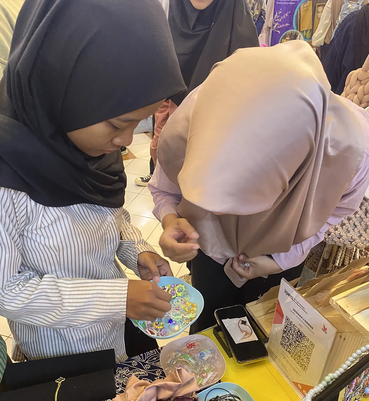 Pengunjung melihat dan memilih aksesori pelengkap di booth Sejukain pada Demo Day WIBAWA UNS 2025. (doc. Tim Sejukain UNS)