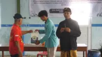 Seorang mahasiswa Universitas Sebelas Maret (UNS) menyerahkan contoh pupuk organik cair hasil olahan eceng gondok Waduk Cengklik kepada warga Desa Ngargorejo, Kecamatan Ngemplak, Kabupaten Boyolali, dalam kegiatan sosialisasi dan pelatihan pemanfaatan eceng gondok sebagai inovasi pertanian berkelanjutan, Rabu (11/12/2025). (doc. pribadi)