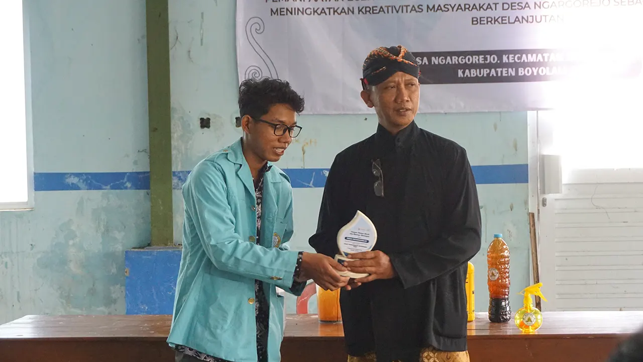 Mahasiswa Universitas Sebelas Maret (UNS) menyerahkan cenderamata kepada perwakilan Desa Ngargorejo pada kegiatan pemanfaatan eceng gondok menjadi pupuk organik cair di Waduk Cengklik, Boyolali. (doc. pribadi)