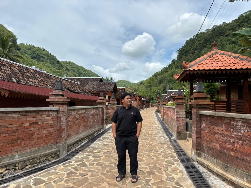 Seorang pengunjung berpose di jalan berbatu Desa Wisata Wotawati, Gunungkidul. Deretan rumah bata merah dan latar perbukitan hijau menambah suasana tenang khas lembah yang menjadi ciri desa ini. (doc. pribadi)