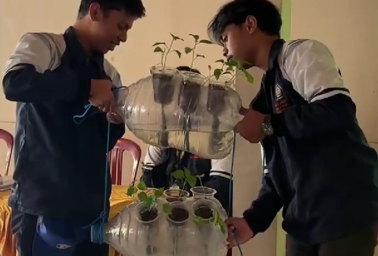 Mahasiswa KKN Tim 1 UNDIP memperagakan proses perakitan aquaponic vertikal garden dari galon bekas sebagai media tanam alternatif dalam kegiatan sosialisasi pemanfaatan lahan terbatas di Desa Pagak, Kabupaten Sragen. (doc. pribadi)