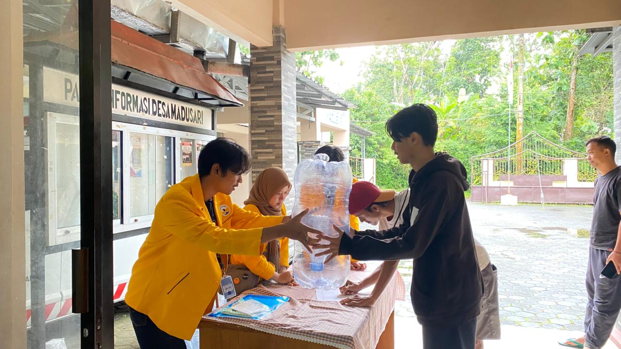 Mahasiswa KKN Universitas Tidar menyerahkan galon bekas kepada warga saat kegiatan sosialisasi pemanfaatan limbah menjadi media budidaya lele dan akuaponik di Balai Desa Madusari, Kabupaten Magelang, Minggu (1/2/2026). (doc. pribadi)