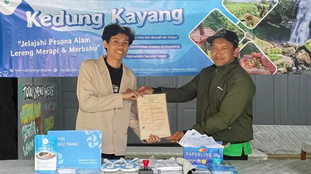 Mahasiswa Ilmu Komunikasi Universitas AMIKOM Yogyakarta, Muhammad Arrasit (kiri), menyerahkan dokumen Hak Kekayaan Intelektual (HKI) logo Wisata Air Terjun Kedung Kayang kepada penanggung jawab destinasi, Surono (kanan), di Desa Wonolelo, Kecamatan Sawangan, Kabupaten Magelang. (doc. Pribadi)