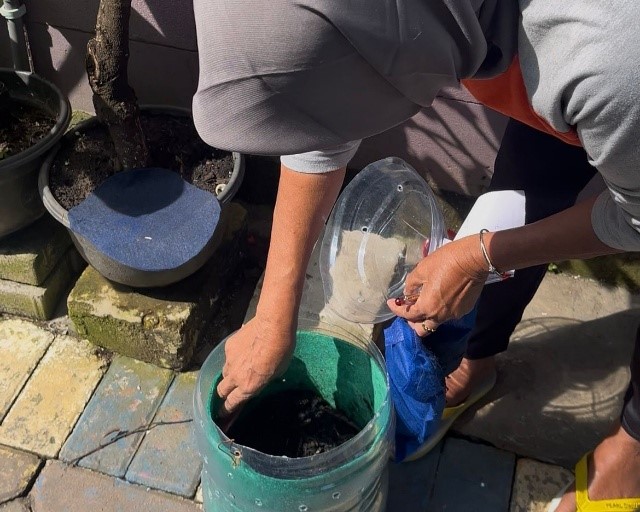 Seorang warga RW 7 Wonokromo memilah sampah organik rumah tangga ke dalam wadah pengolahan kompos di lingkungan permukiman Surabaya, beberapa waktu lalu. (doc. pribadi)