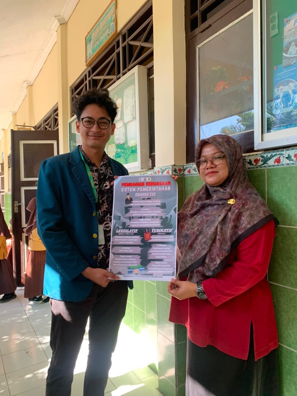 Mahasiswa KKN UNDIP saat menyerahkan poster edukasi tentang sistem pemerintahan. (Dok. Pribadi)