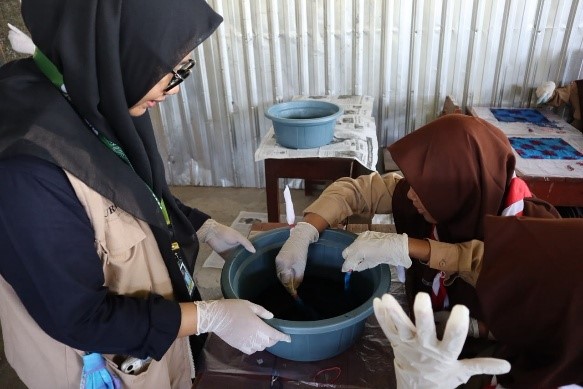 Mahasiswa KKN UNS Kelompok 41 mendampingi siswa dalam proses pewarnaan kain menggunakan pewarna Remasol. (Dok. KKN UNS Kelompok 41)