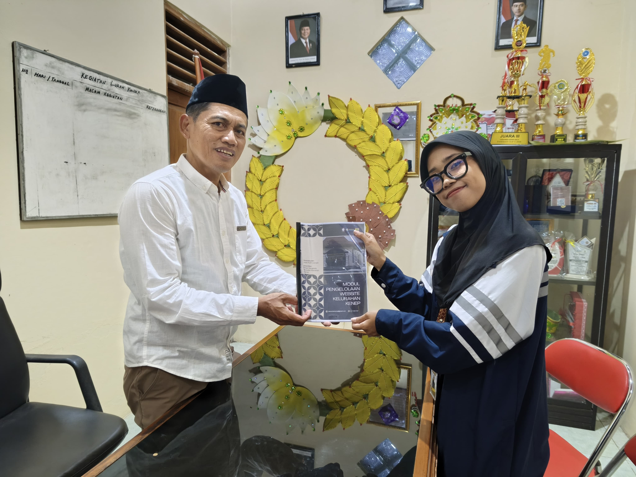 Penyerahan modul fisik pengelolaan website Kelurahan Kenep kepada Lurah Kenep, Muh. Shidiq Pramana, S.E., sebagai bagian dari luaran program kerja sosial kemasyarakatan KKNT IDBU 64, Minggu (16/8/2026). Modul tersebut diharapkan menjadi panduan bagi perangkat kelurahan dalam mengelola dan memperbarui informasi website secara mandiri dan berkelanjutan. (Doc. Pribadi)