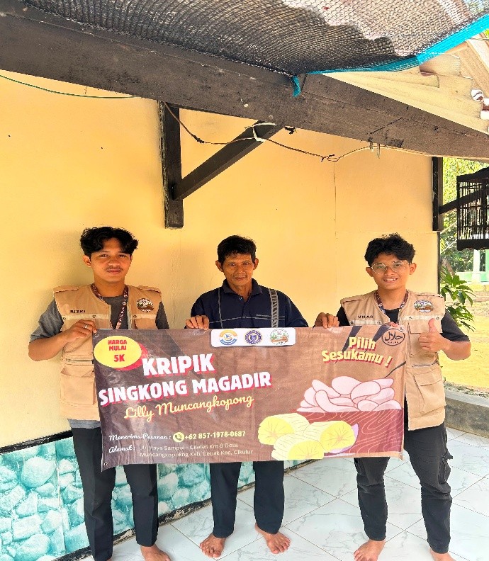 Mahasiswa mencetak banner usaha yang informatif dan menarik. Banner yang menampilkan merek usaha, varian rasa original dan balado, serta kontak pemesanan tersebut dipasang langsung di area tempat usaha Lilly Magadir. (Dok. Pribadi/Mahasiswa (KKM) Kelompok 82)